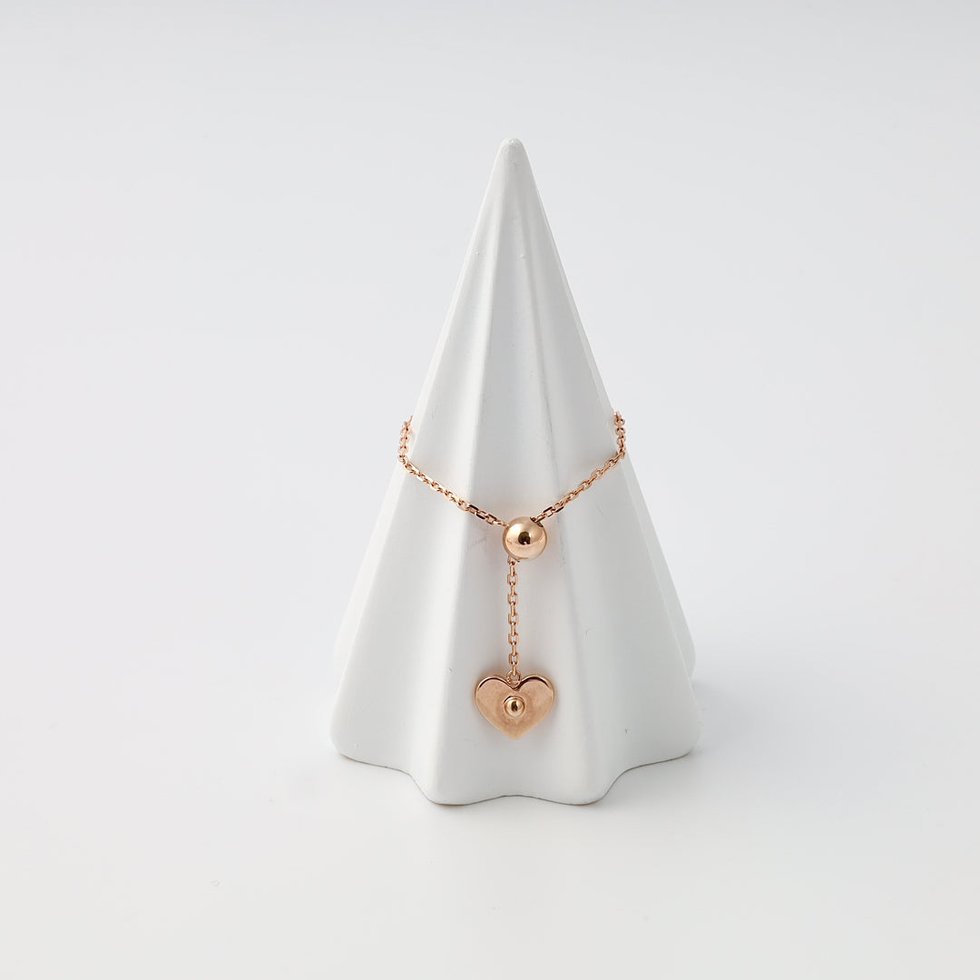 Rose gold 14k gold bracelet with bead and heart charm on display cone, Ukrainian Jewelry, dainty gold chain bracelet gift.
