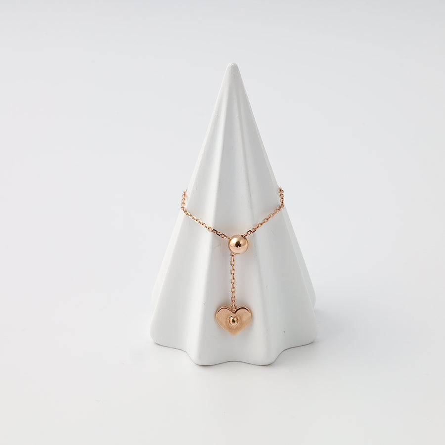 Rose gold 14k gold bracelet with bead and heart charm on display cone, Ukrainian Jewelry, dainty gold chain bracelet gift.