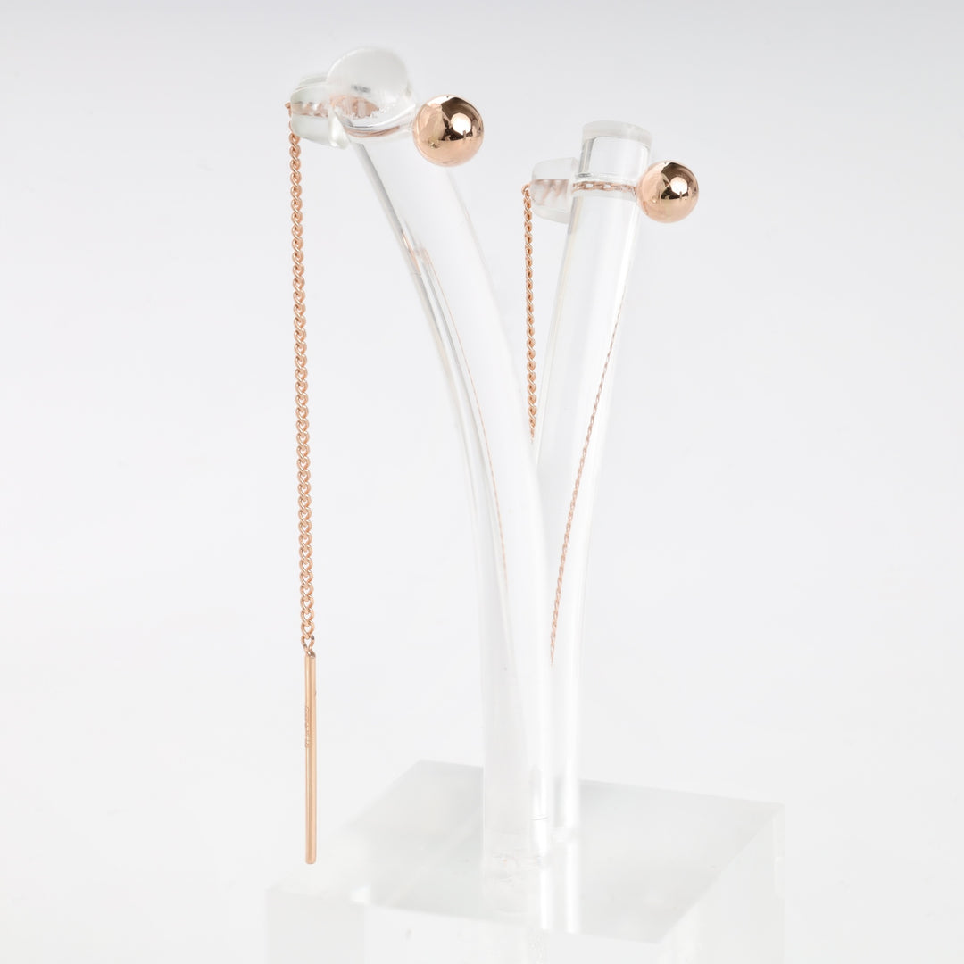 Rose gold threader earrings with ball studs and fine chains displayed on a clear acrylic stand.