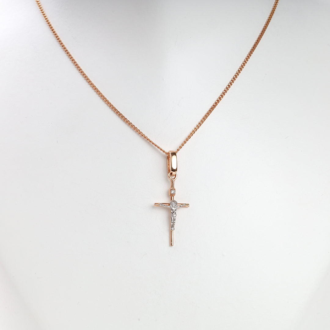 Rose gold crucifix pendant necklace with silver Jesus motif displayed on a white mannequin bust.
