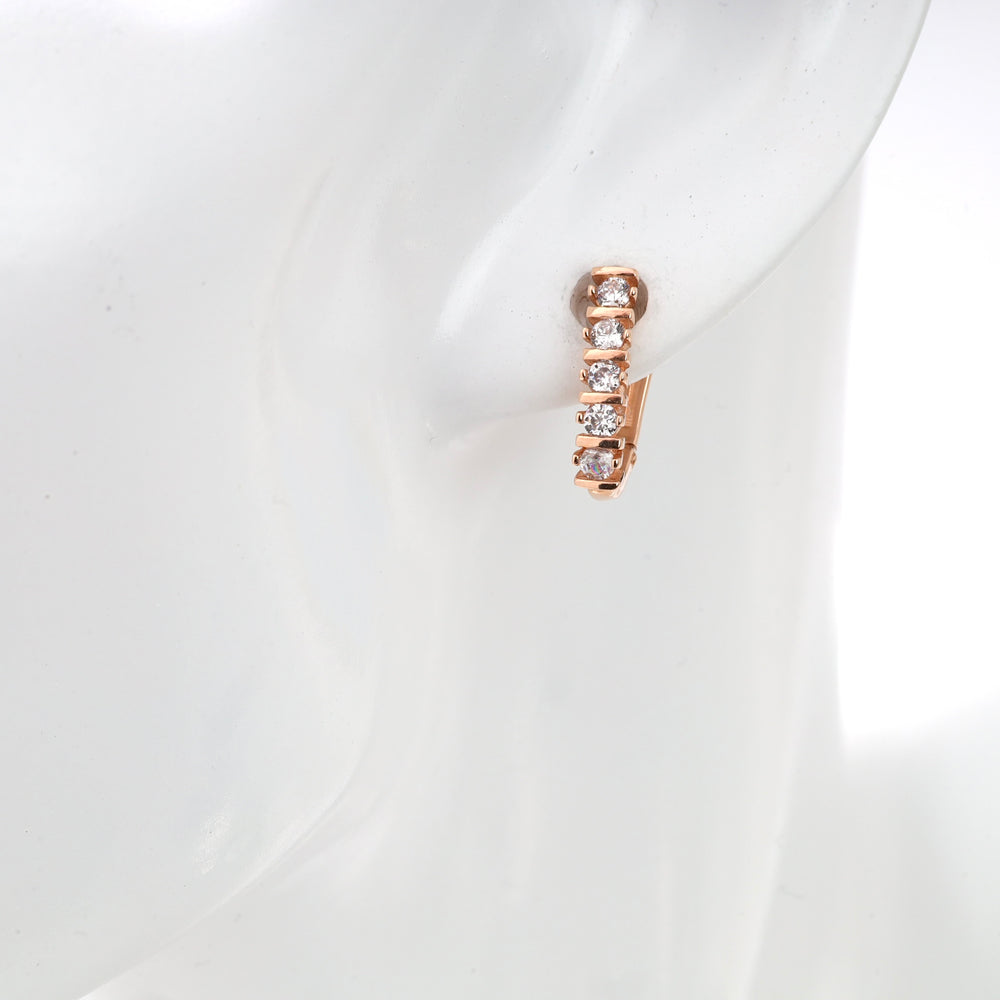 Rose gold hoop earring with cubic zirconia stones on mannequin ear.