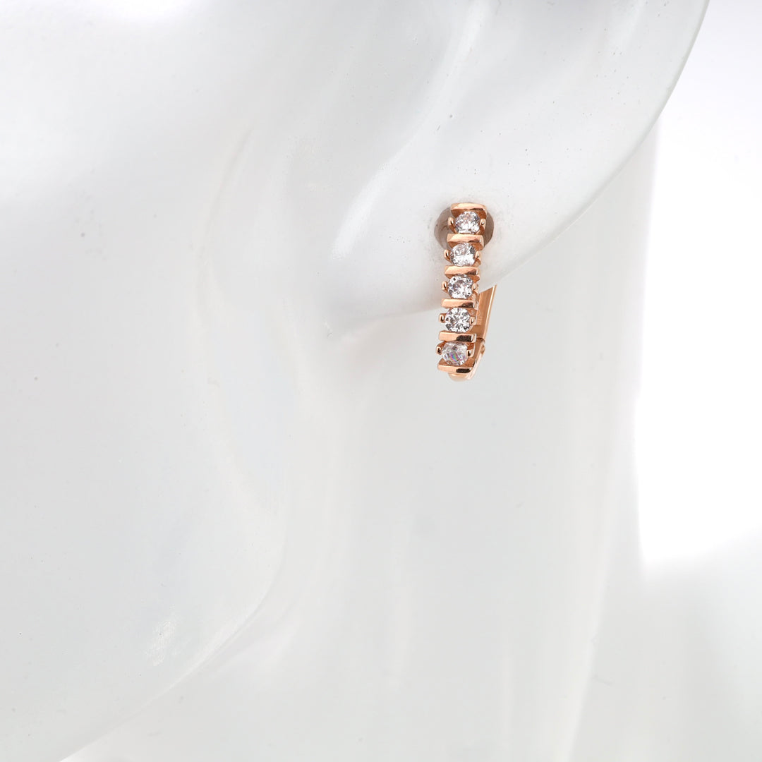 Rose gold hoop earring with cubic zirconia stones on mannequin ear.