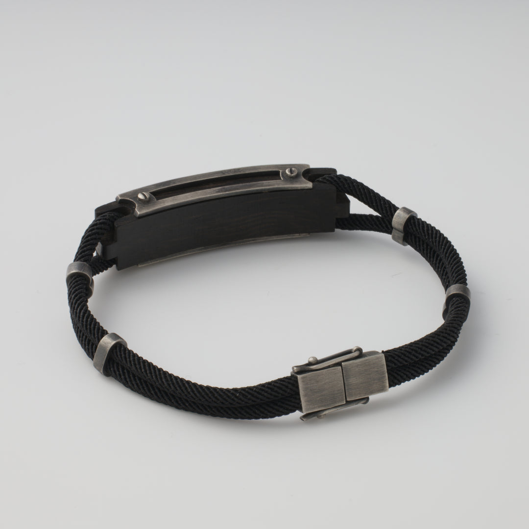Black rope bracelet with a rectangular metal plate and clasp, shown on a white background. Men's bracelet, stainless steel jewelry.