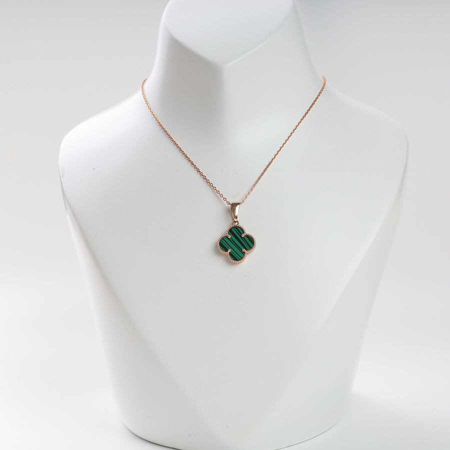Gold necklace with a green malachite clover pendant displayed on a white jewelry bust.