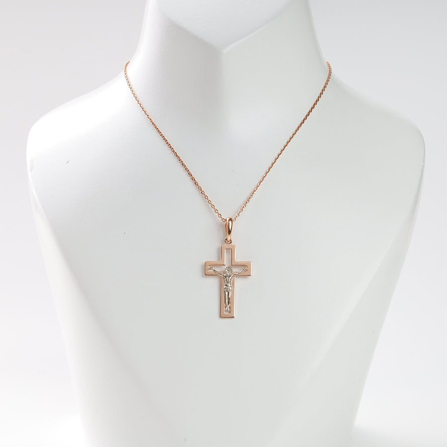 Rose gold crucifix pendant necklace with a silver Jesus motif displayed on a white jewelry bust.