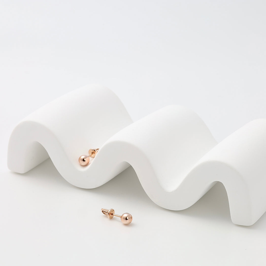 Pair of small 14k gold ball stud earrings on white display, minimalist Ukrainian Jewelry, simple gold stud earrings for women.