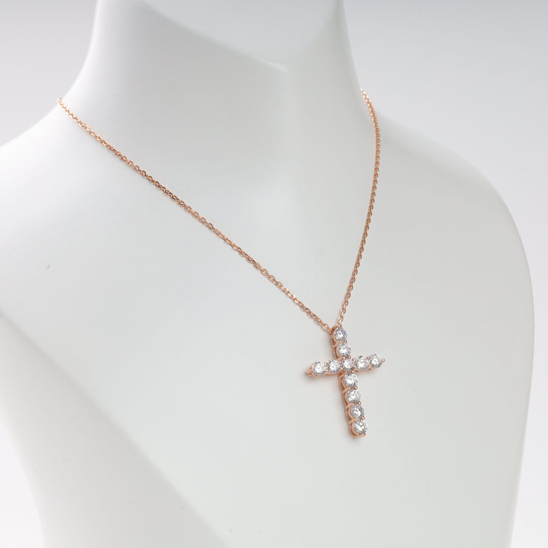 Rose gold chain necklace with a crystal-studded cross pendant displayed on a white bust.