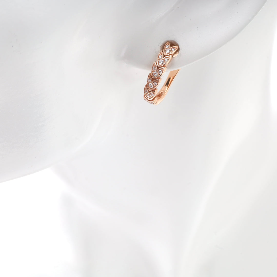 Rose gold leaf motif hoop earring with small clear stones on a mannequin's ear.