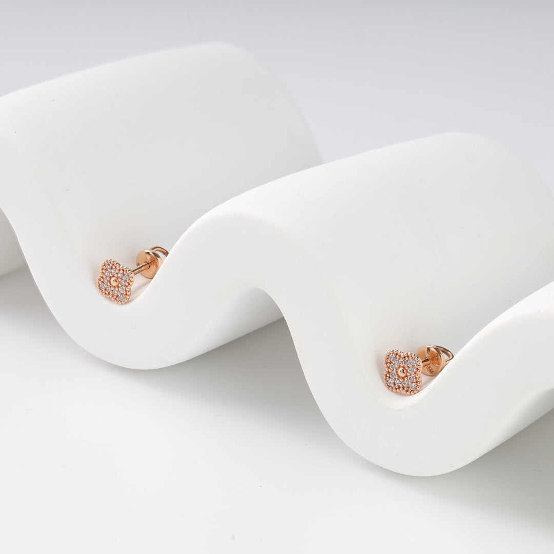 Square rose gold stud earrings with clear crystal pavé, displayed on a white wavy stand, minimalist jewelry.