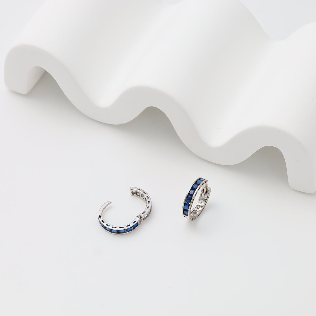 Sterling silver blue stone huggie hoop earrings on white display, Ukrainian Jewelry, small silver hoop earrings for women.