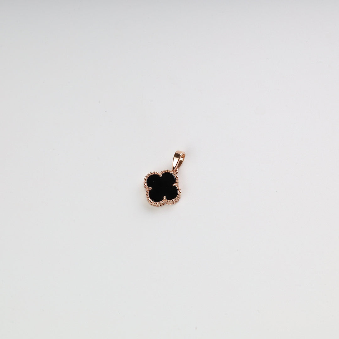 Gold clover pendant with black enamel center on a white background, jewelry charm, gold necklace pendant.