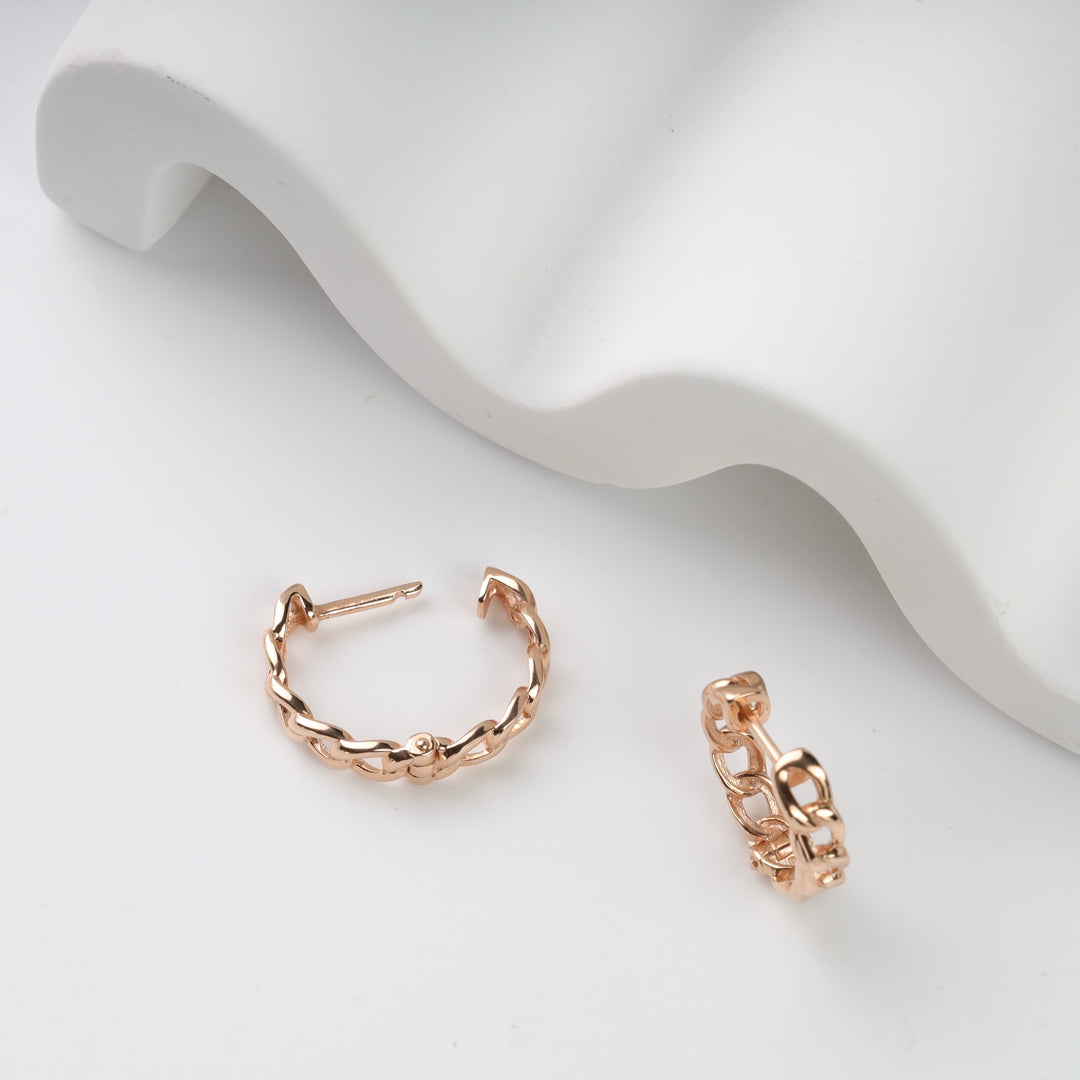 Rose gold chain link hoop earrings displayed on a white surface.