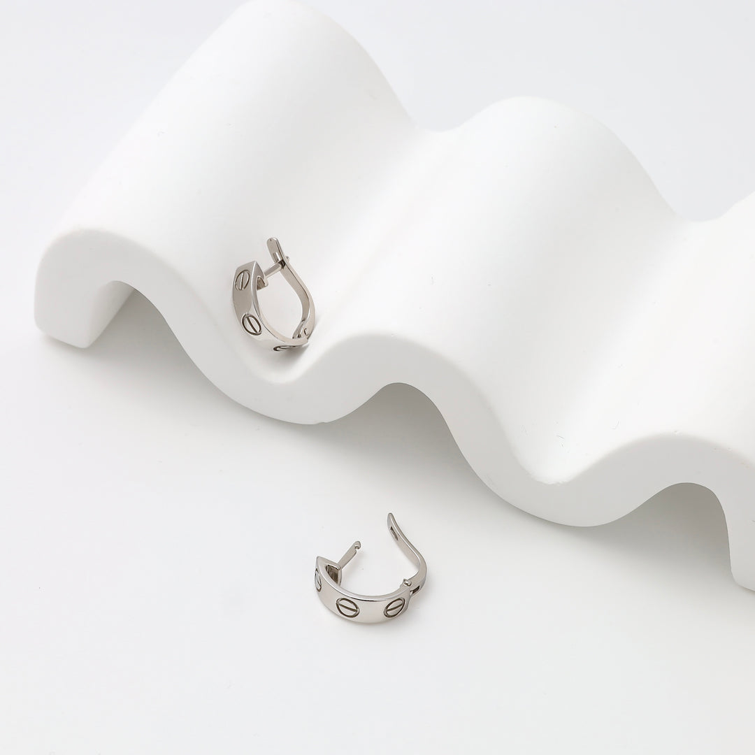 Sterling silver huggie hoop earrings with engraved circle motif on white display, minimalist Ukrainian Jewelry for everyday wear.