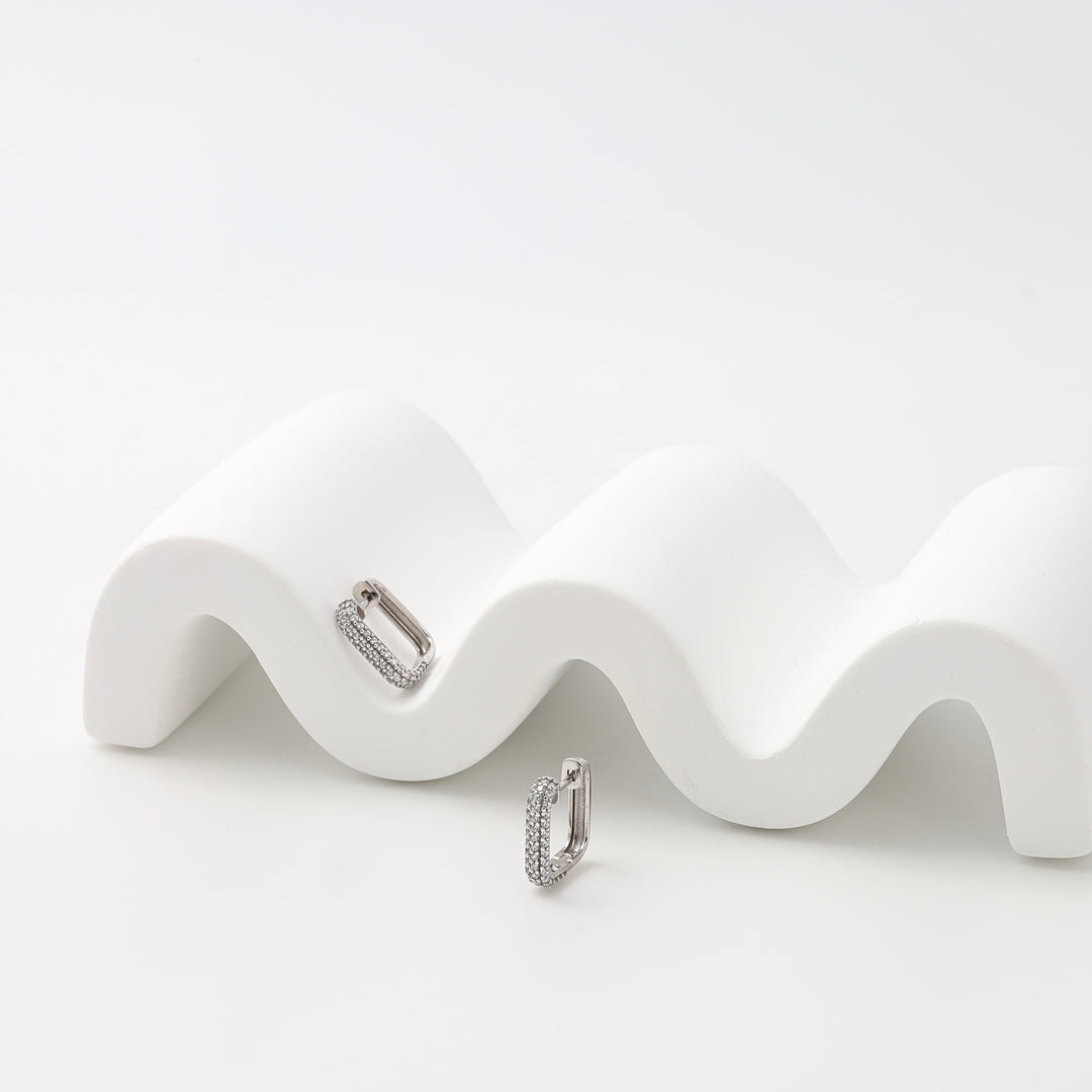 Sterling silver pavé huggie hoop earrings on white display, minimalist everyday Ukrainian Jewelry, silver huggie earrings.