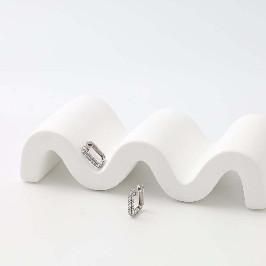 Sterling silver pavé huggie hoop earrings on white display, minimalist everyday Ukrainian Jewelry, silver huggie earrings.