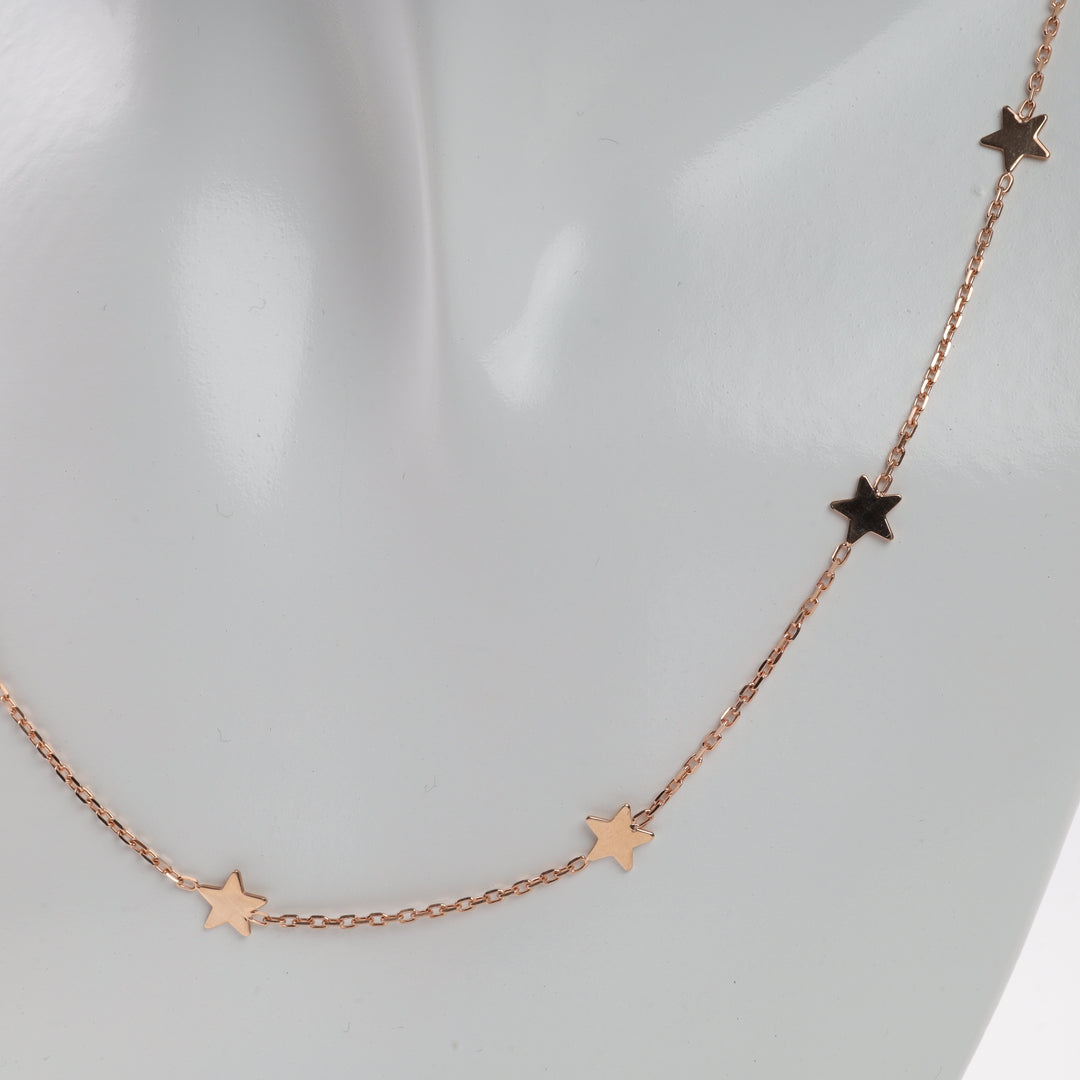 Rose gold necklace with star charms on mannequin bust. Star charm necklace, rose gold jewelry, delicate chain.