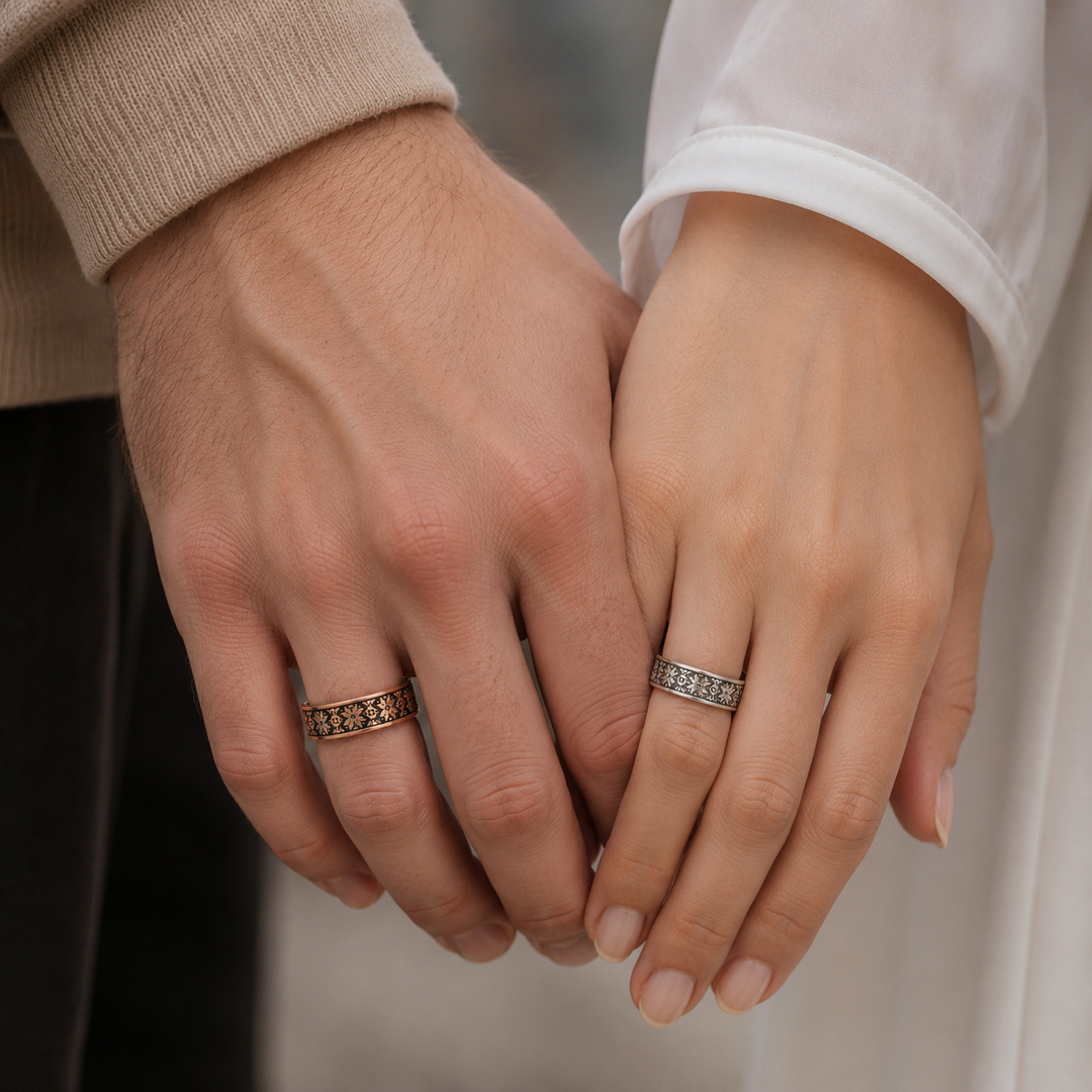 Couple holding hands wearing Ukrainian vyshyvanka wedding bands, rose gold on his hand and white gold on hers