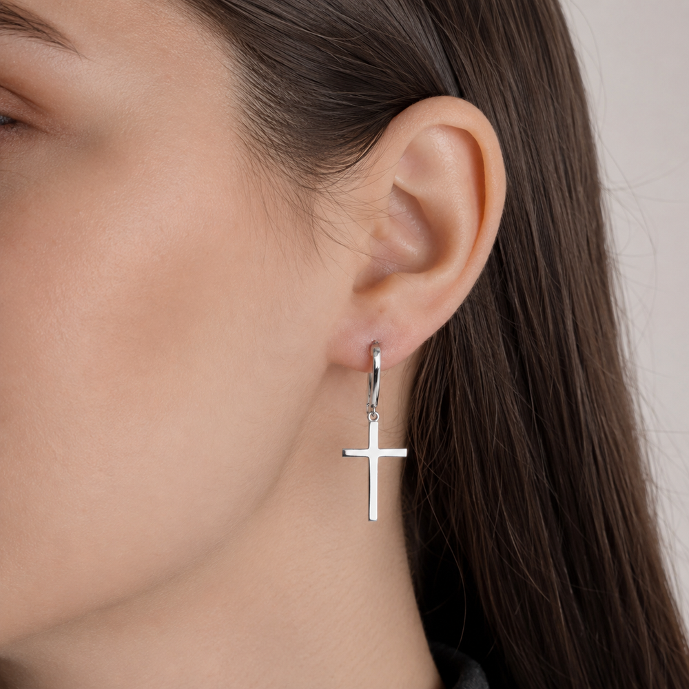 Model wearing a silver 925 cross drop earring on a hinged hoop
