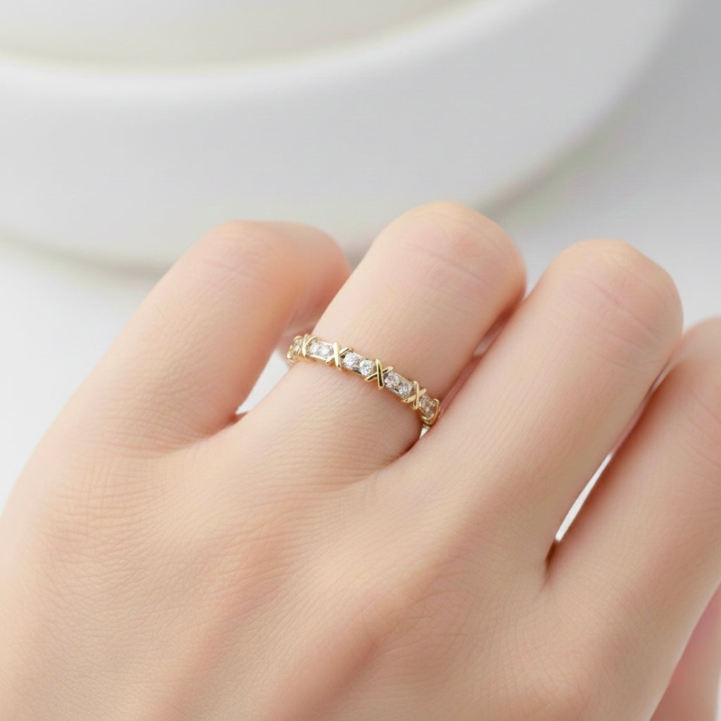 Gold ring with small stones on a finger against a white background