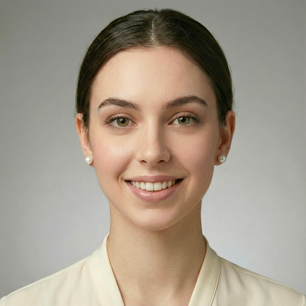 Woman with a neutral expression against a gray background white pearl earrings