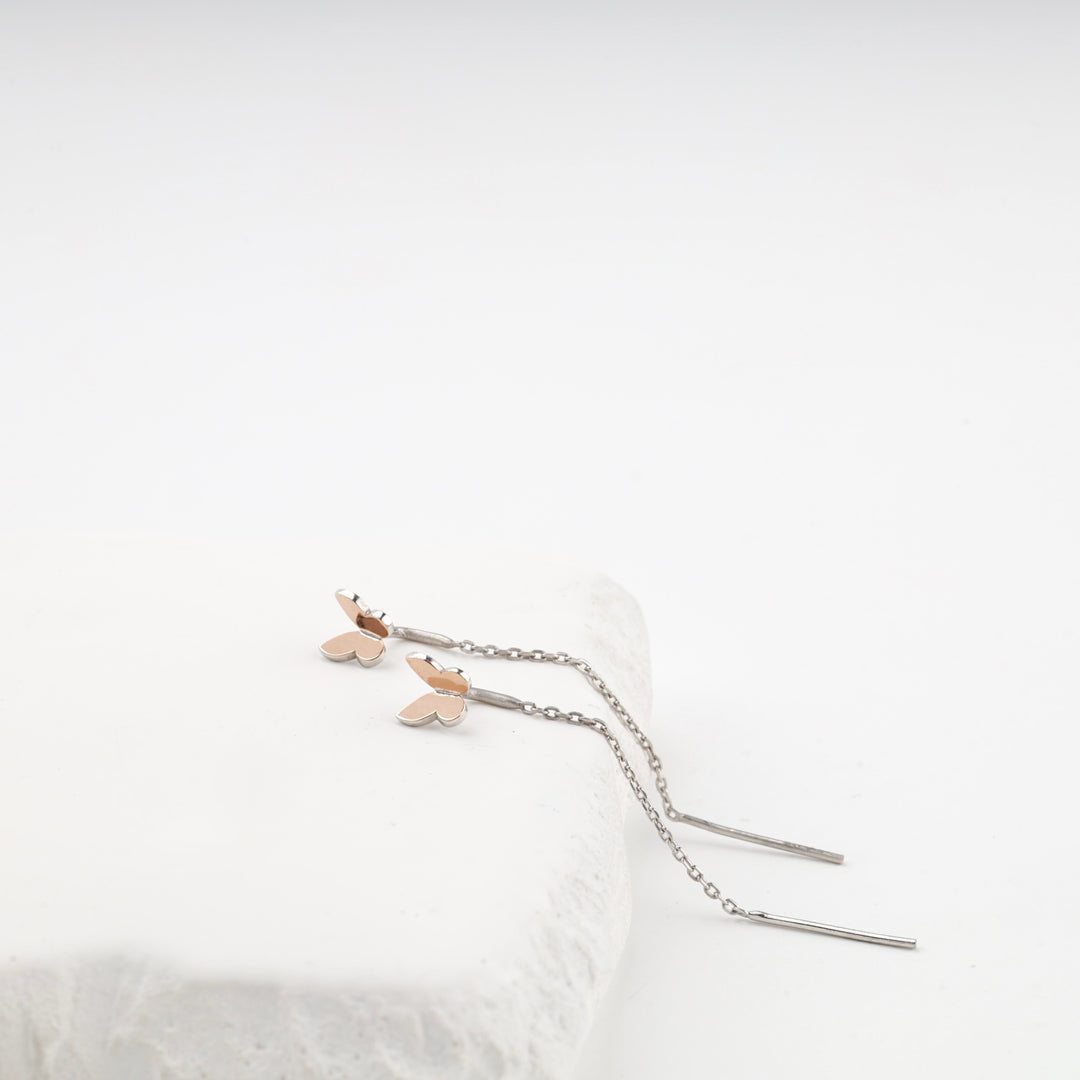 Silver 925 threader earring with a rose gold butterfly on a white surface