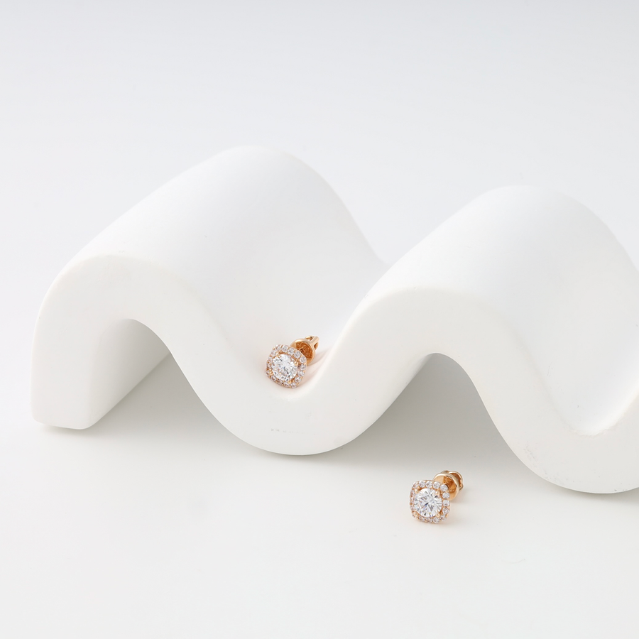 Pair of rose gold earrings screw-back on a white wavy surface