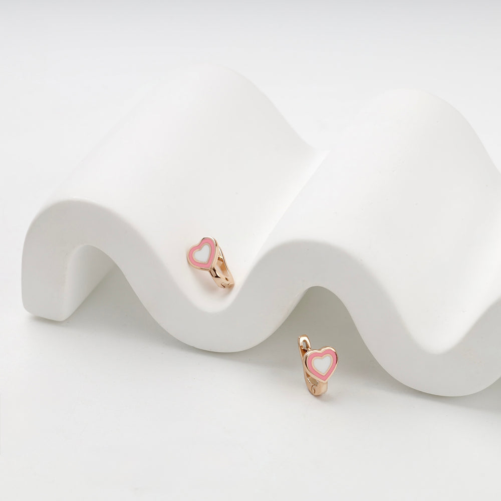 Pink and white enamel heart earrings in 14K rose gold on a sculptural white backdrop