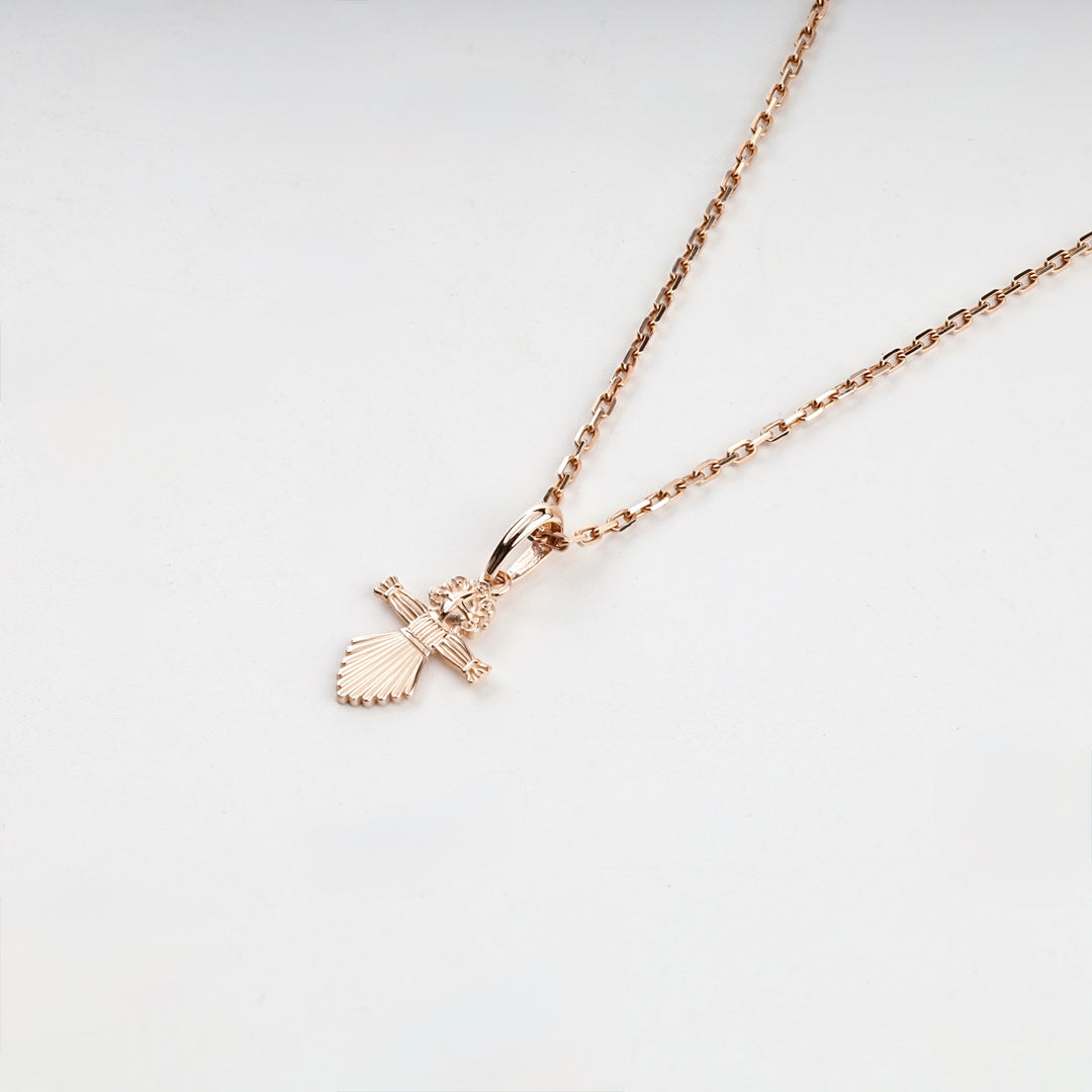 Rose gold Ukrainian motanka doll pendant on a chain, angled view