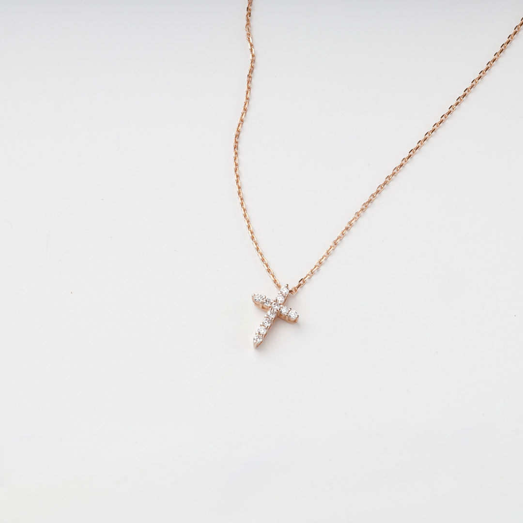 Small rose gold cross pendant with cubic zirconia on a chain, front view