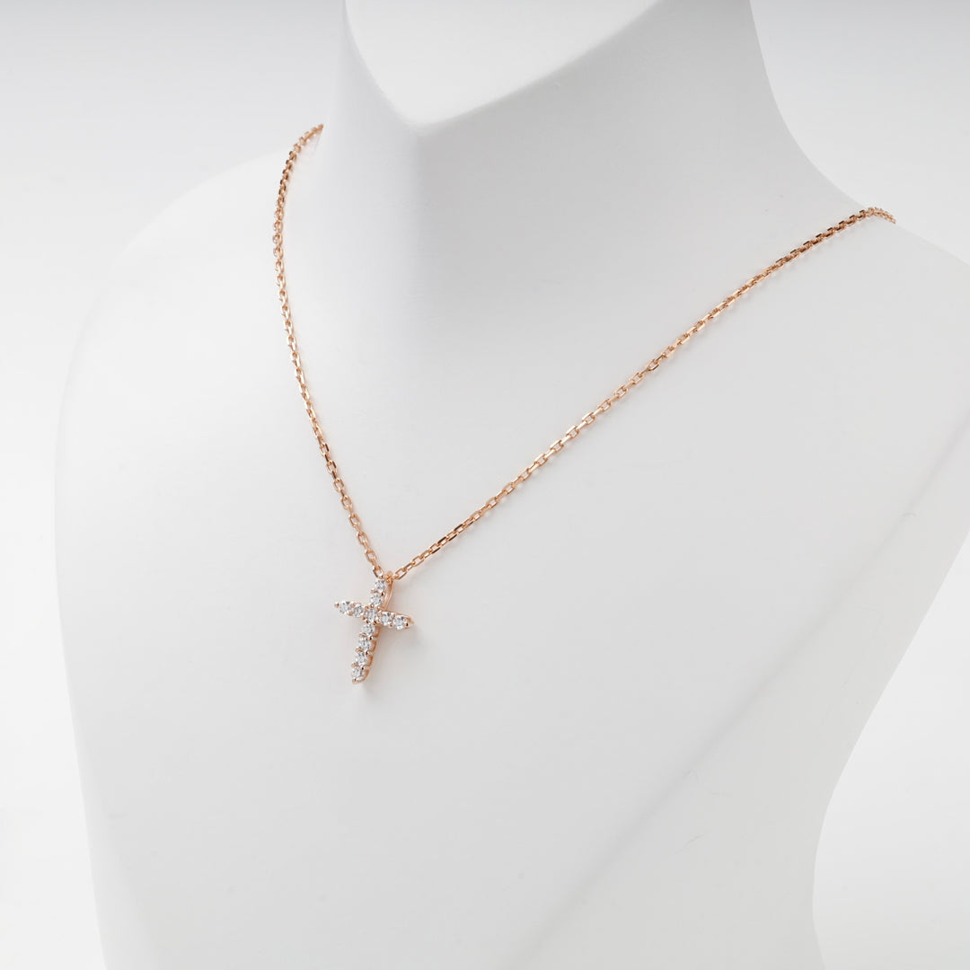 Miniature rose gold cubic zirconia cross pendant, angled view