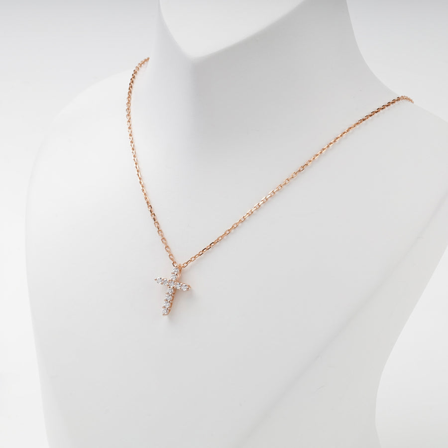 Miniature rose gold cubic zirconia cross pendant, angled view