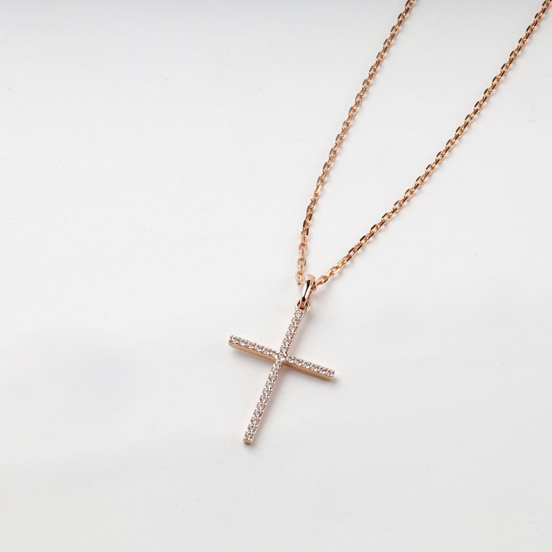 Slim rose gold cross pendant with cubic zirconia on a chain, front view