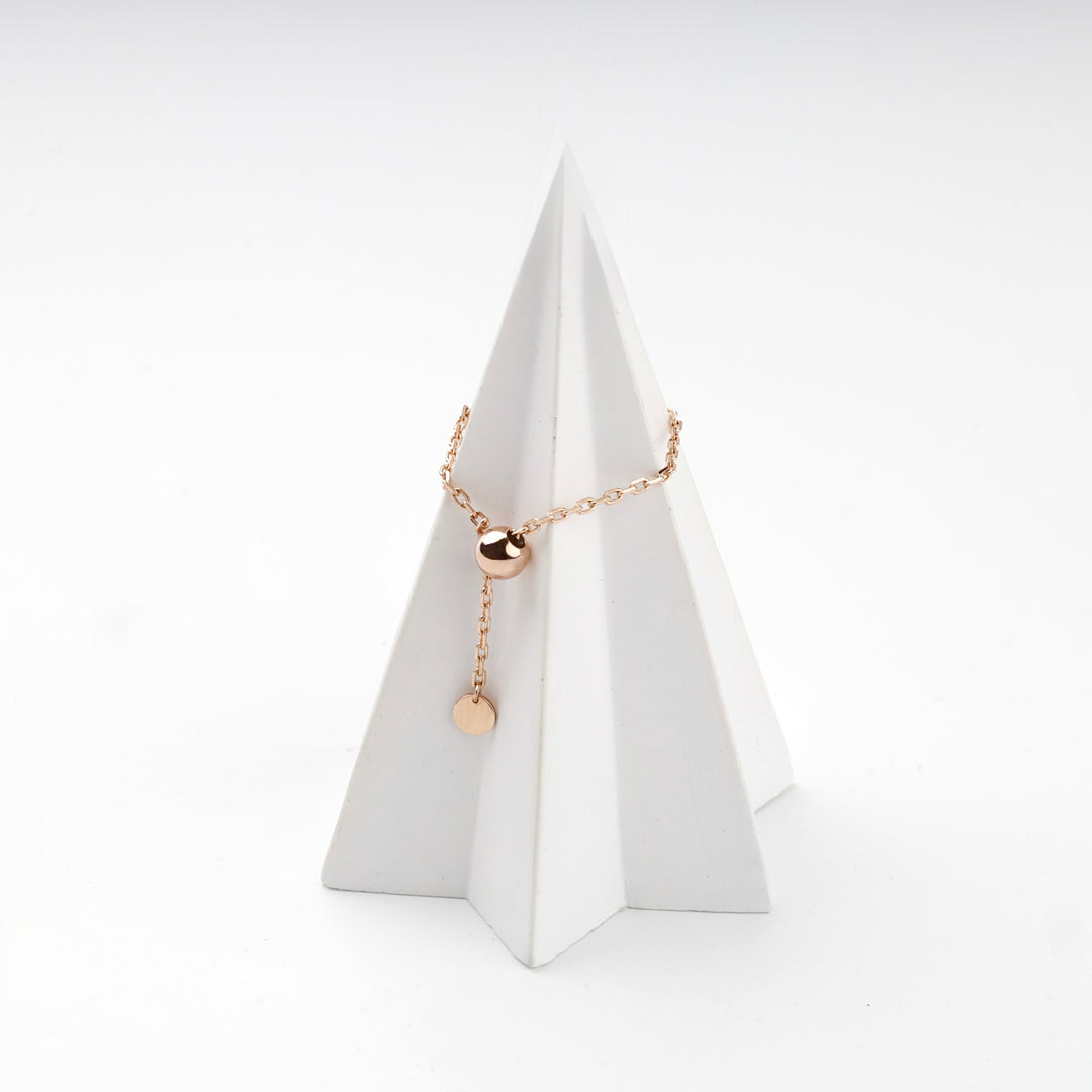 Rose gold chain ring with a polished gold ball on a white display cone