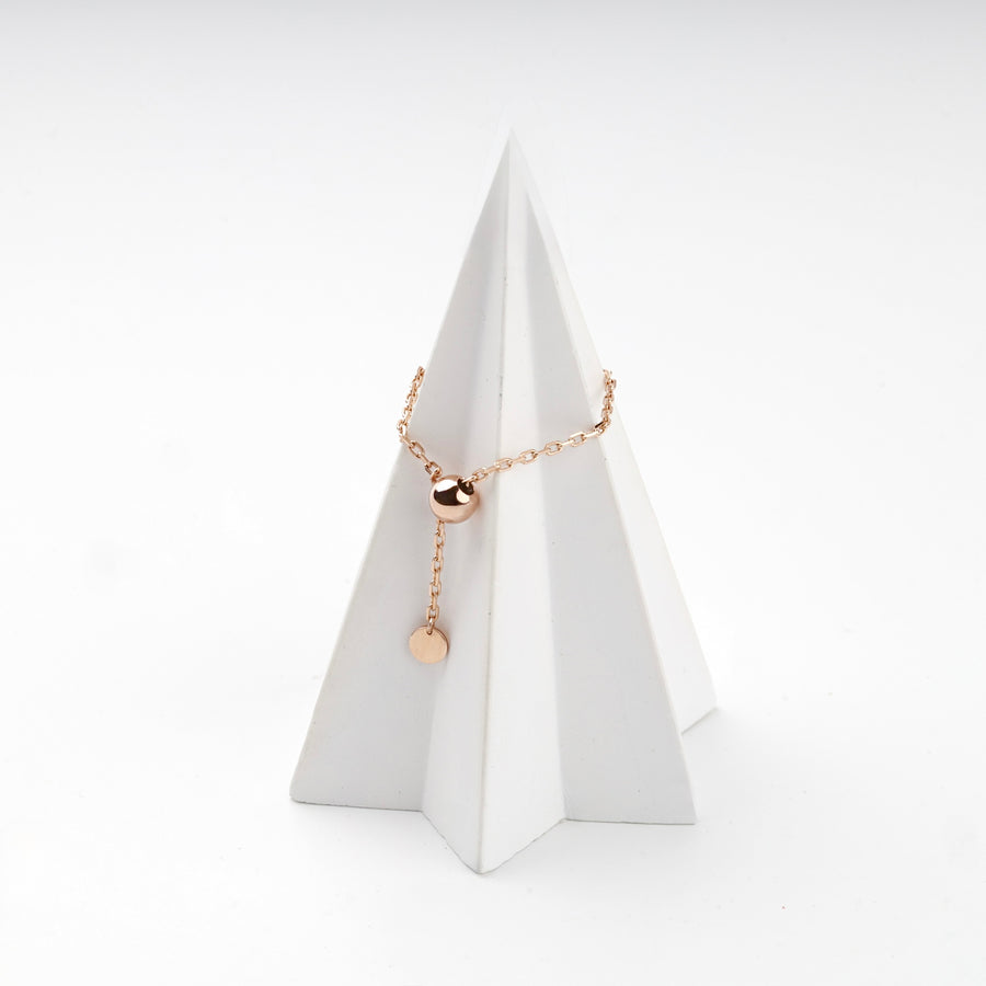 Rose gold chain ring with a polished gold ball on a white display cone