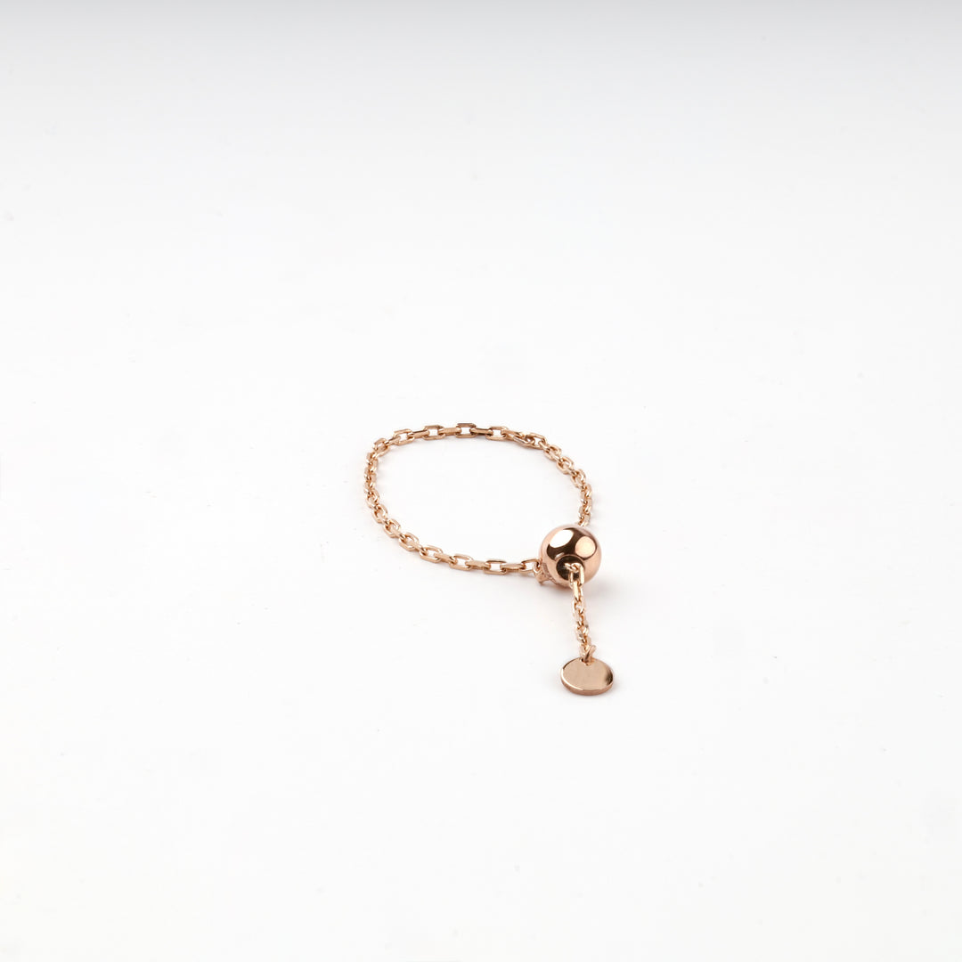 Rose gold chain ring laid flat, showing the gold ball and the round disc charm