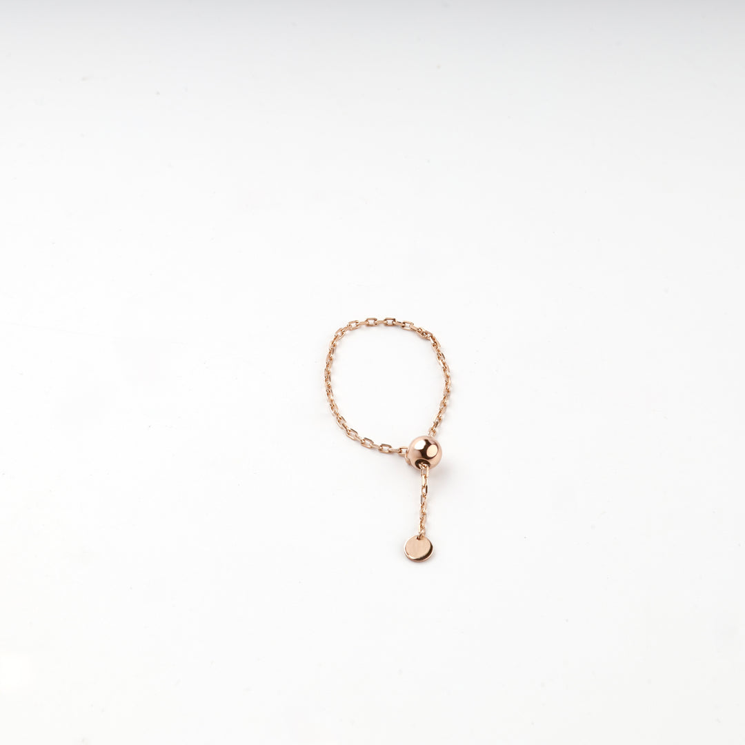 Overhead view of the rose gold ball chain ring on a white surface