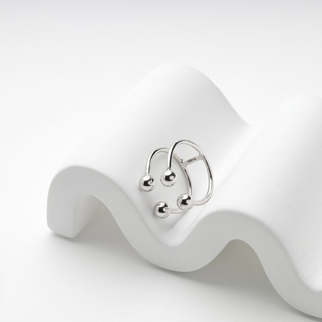 Silver 925 four ball ring resting on a white wave prop