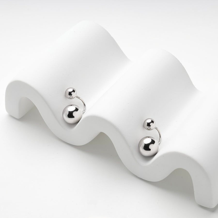 Silver 925 ball duo earrings resting on a white wave stand