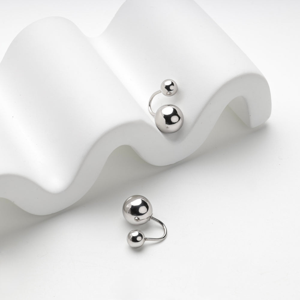Ball duo earring with a large and a small polished silver sphere, angled view