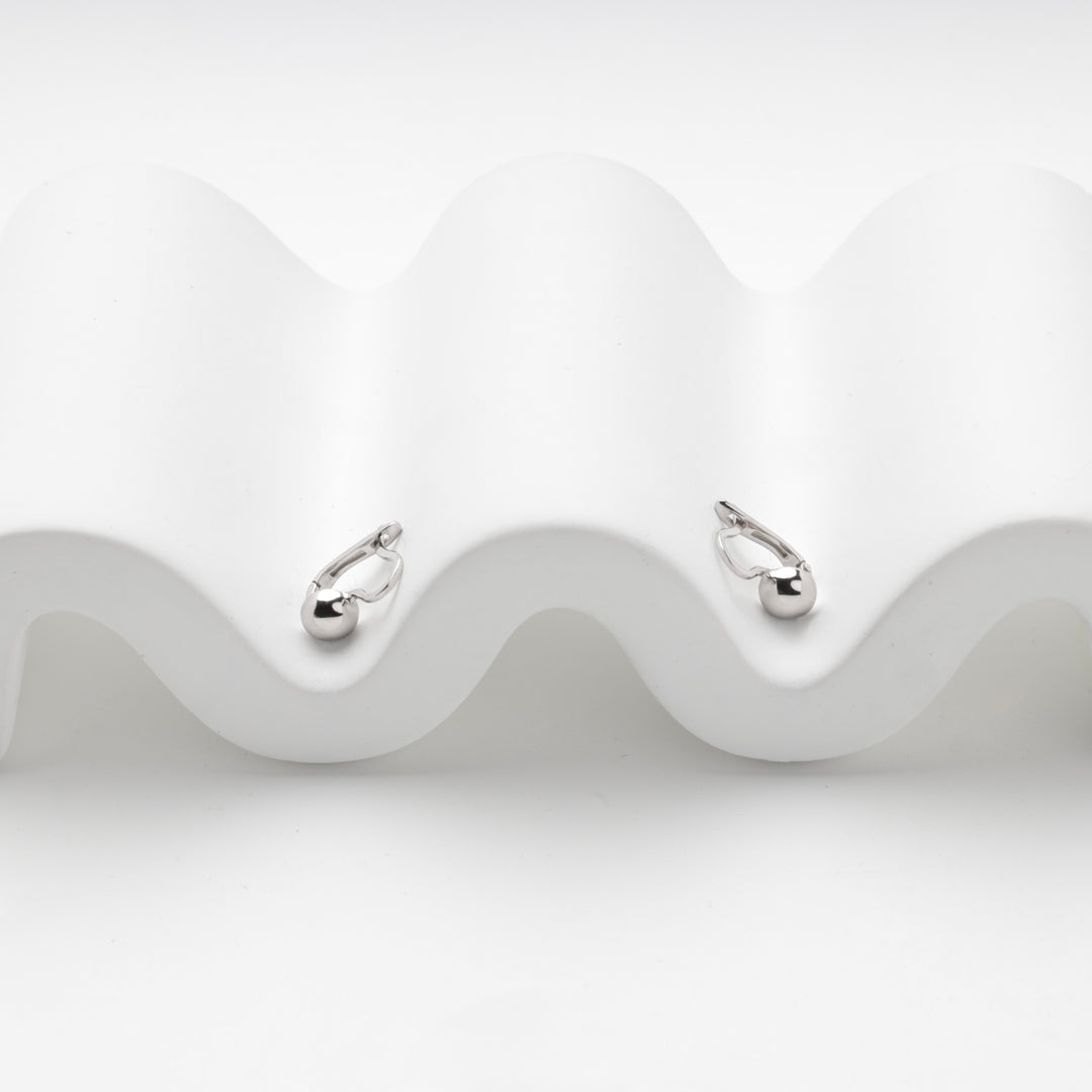 Silver 925 leverback earrings with balls shown on a wave stand