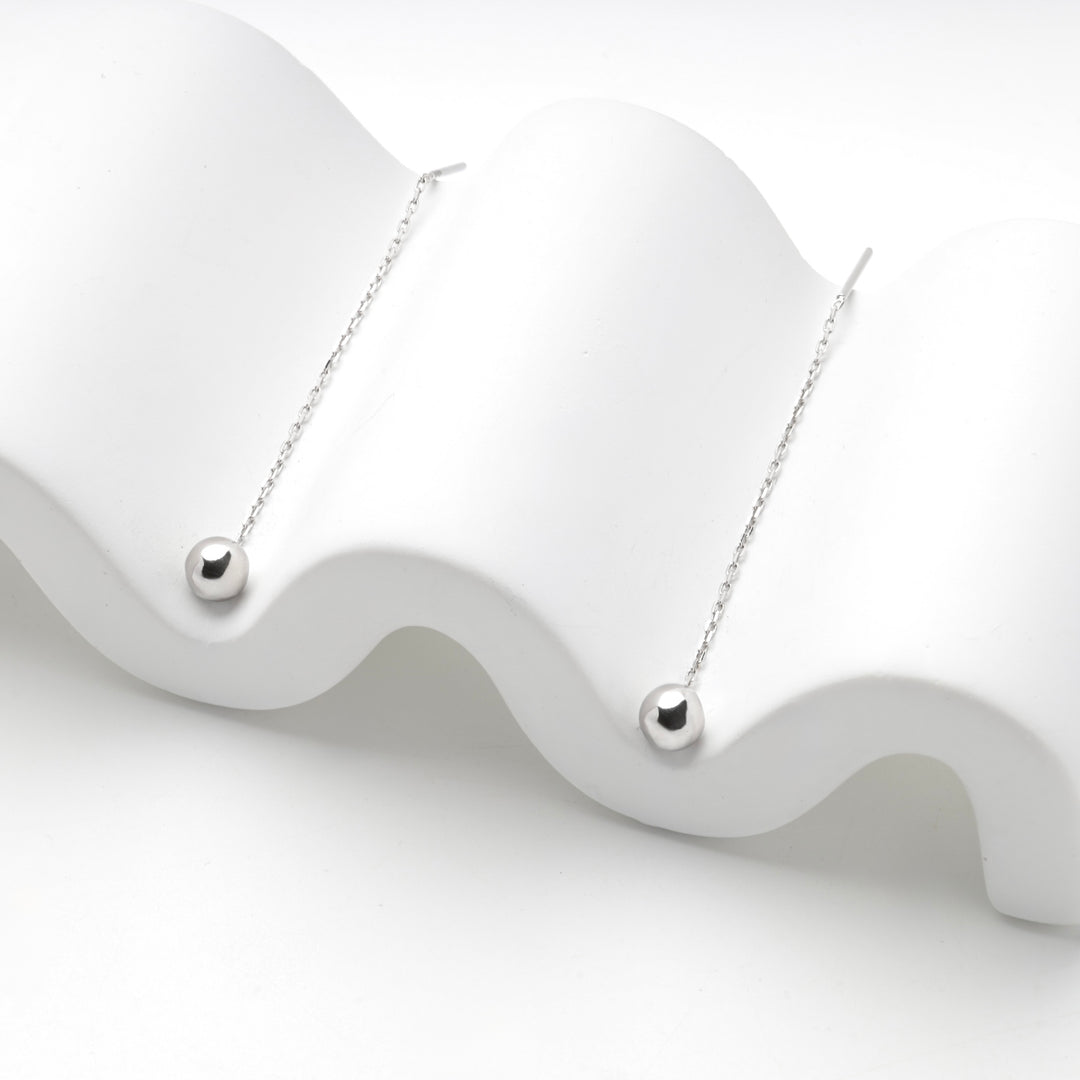 Silver 925 ball threader earrings draped over a white wave stand