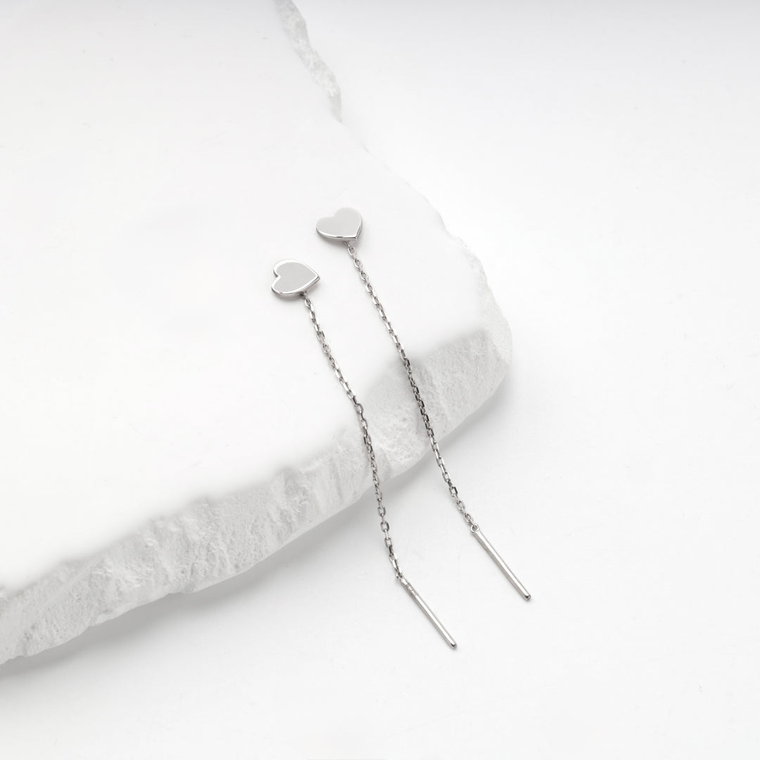 Silver 925 heart threader earrings with chains hanging over the edge of a stone slab