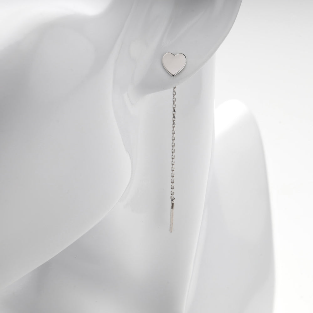 Close view of the flat silver heart resting on the lobe of a mannequin