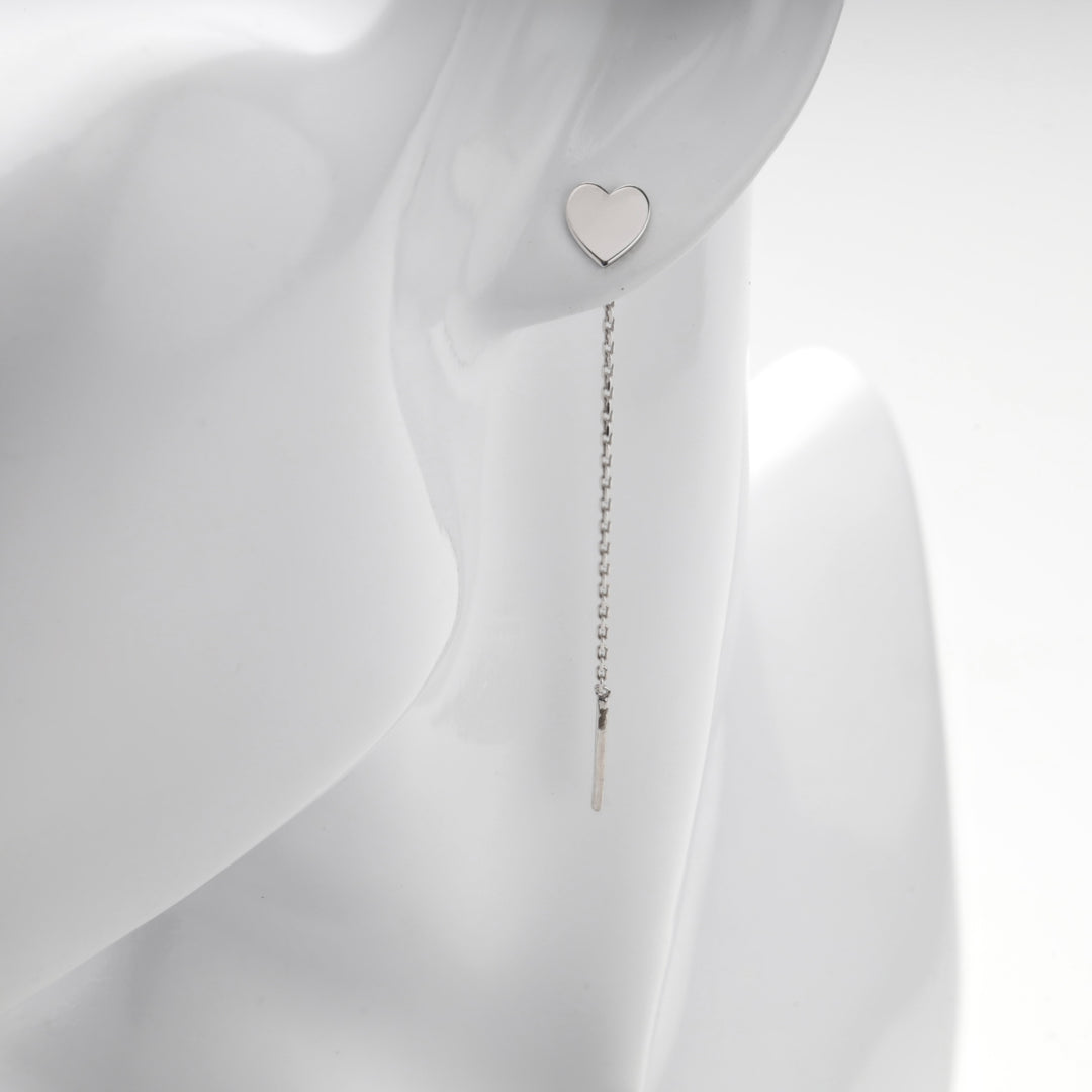 Close view of the flat silver heart resting on the lobe of a mannequin