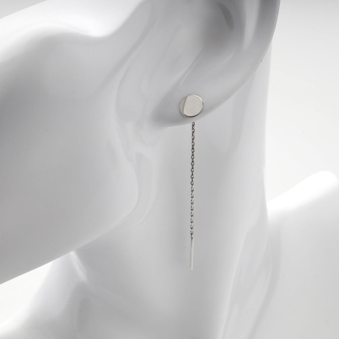 Close view of the flat silver disc at the lobe of a mannequin