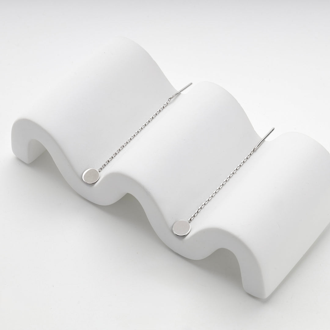 Silver 925 disc threader earrings resting on a white wave stand