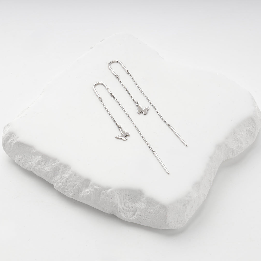 Silver 925 butterfly threader earrings on a white stone slab