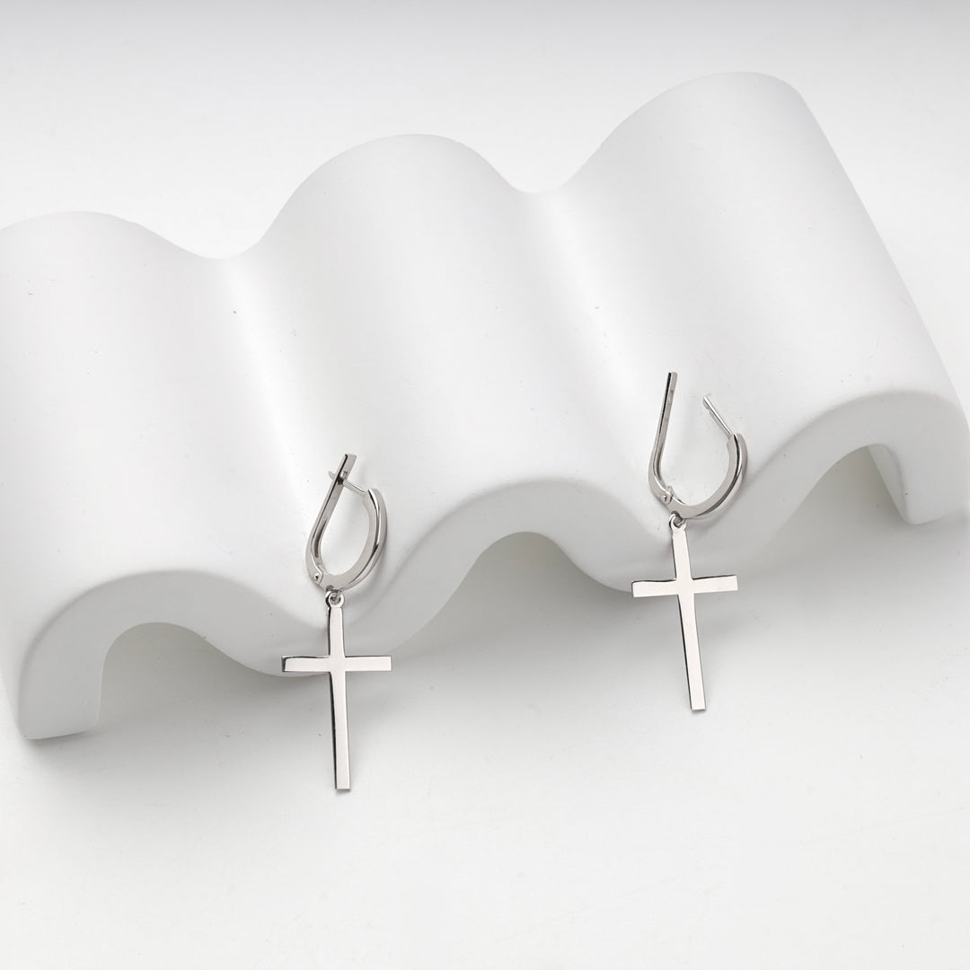 Silver 925 cross earrings resting on a white wave display stand