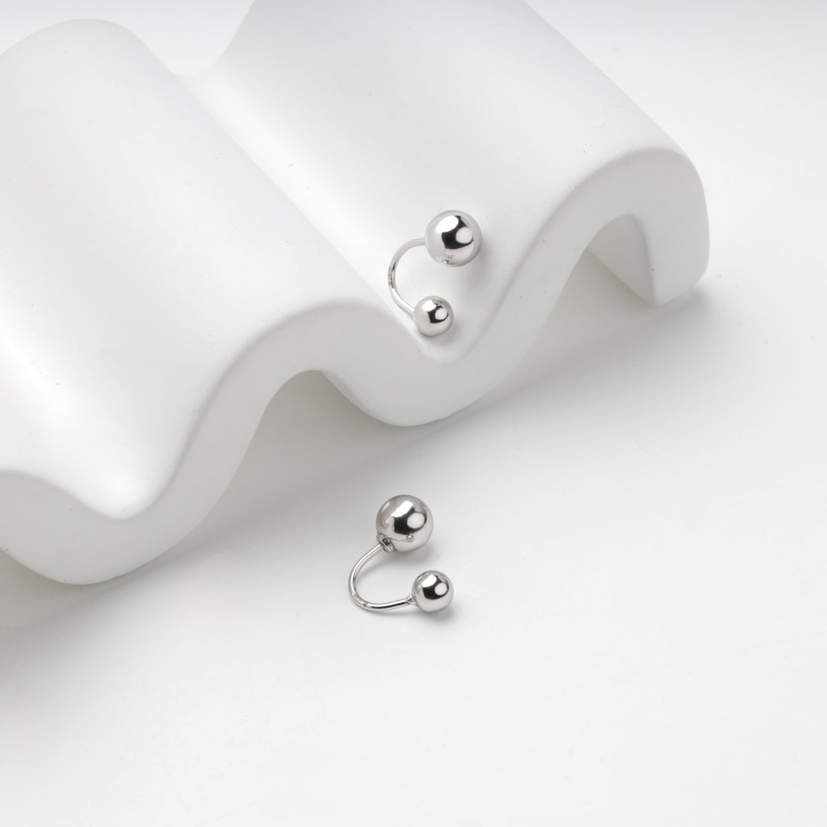 Silver 925 double ball earrings on a white wave stand