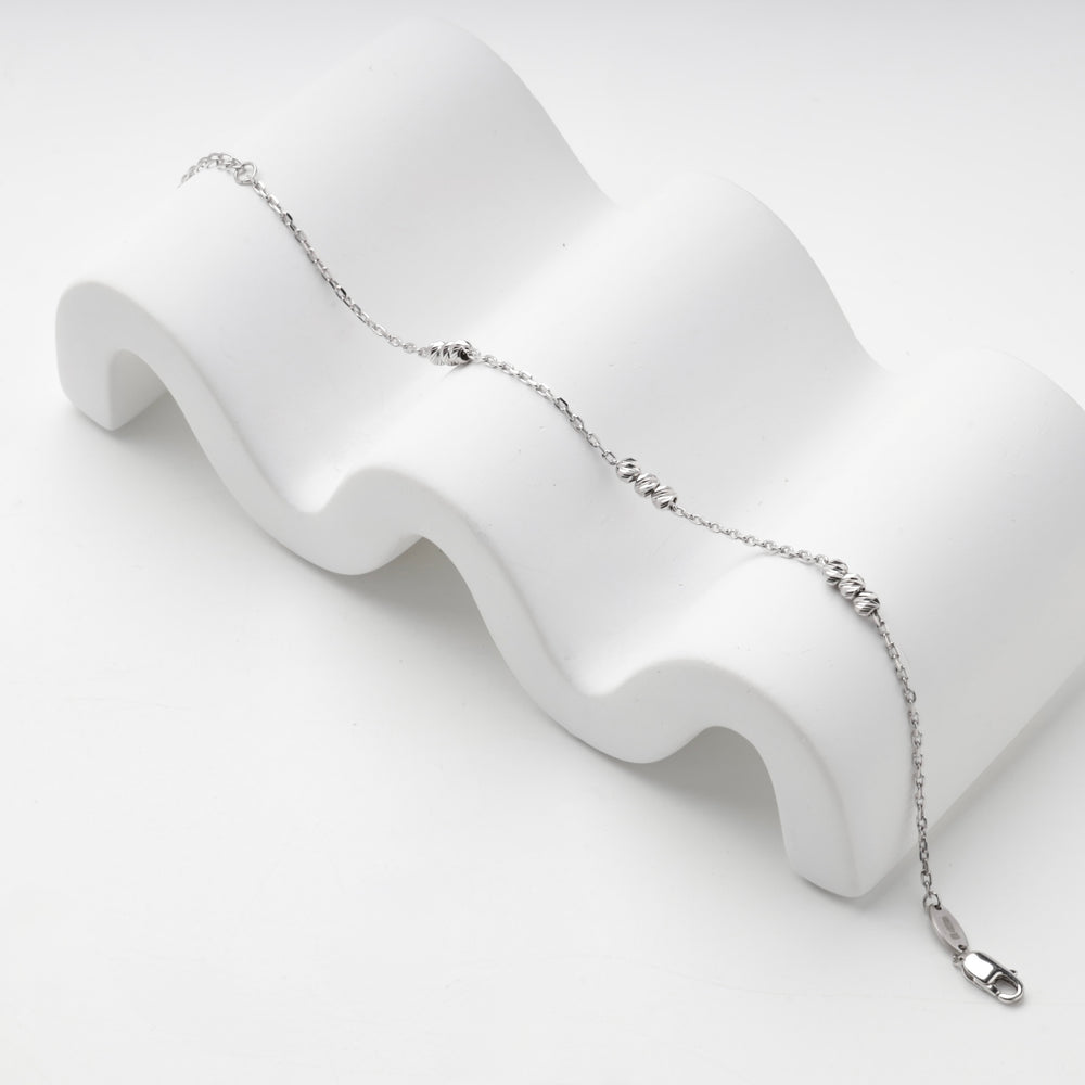Silver 925 bracelet draped over a white wave-shaped display block